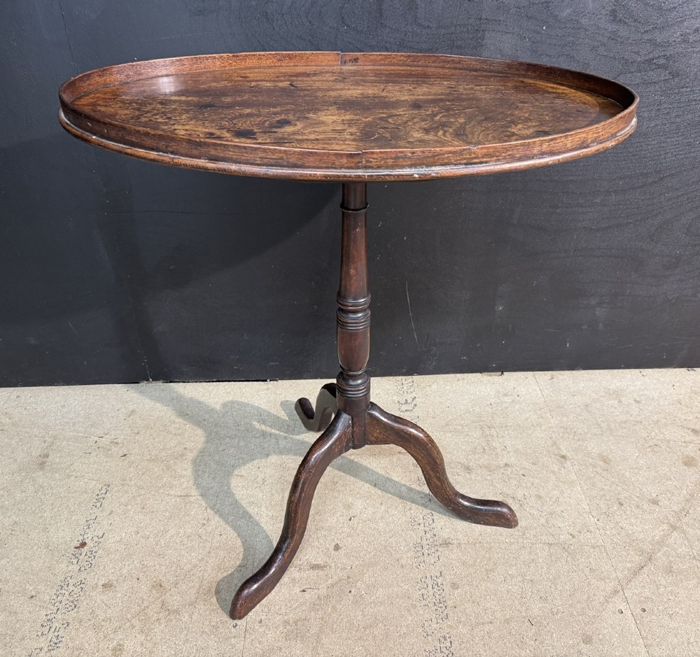 A Georgian mahogany tilt-top table featuring a circular top raised on a turned pedestal column and tripod cabriole legs.