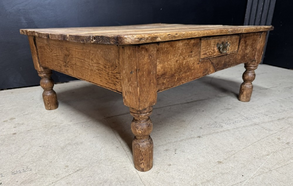 A low rectangular rustic pine coffee table featuring a plank top, turned corner legs, and a single central drawer with a brass drop handle. View VII