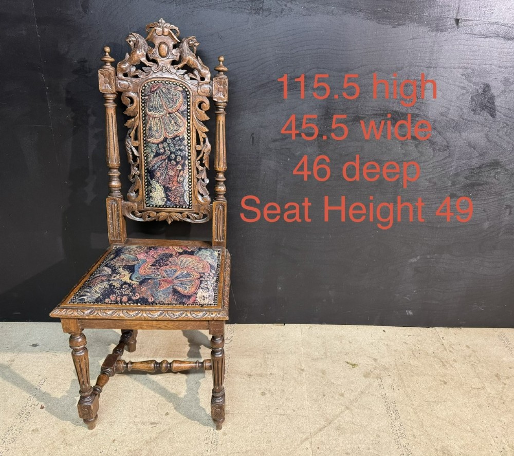A set of eight high-backed dark oak dining chairs featuring carved lion crests and tapestry fabric upholstery. View VIII