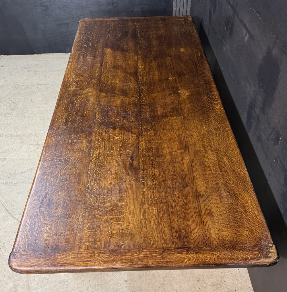A long and deep solid dark oak farmhouse dining table featuring a plank top, moulded apron, and thick turned baluster legs joined by a floor-level stretcher. View V