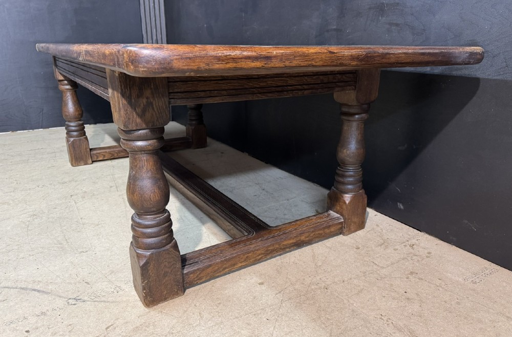 A long and deep solid dark oak farmhouse dining table featuring a plank top, moulded apron, and thick turned baluster legs joined by a floor-level stretcher. View VIII