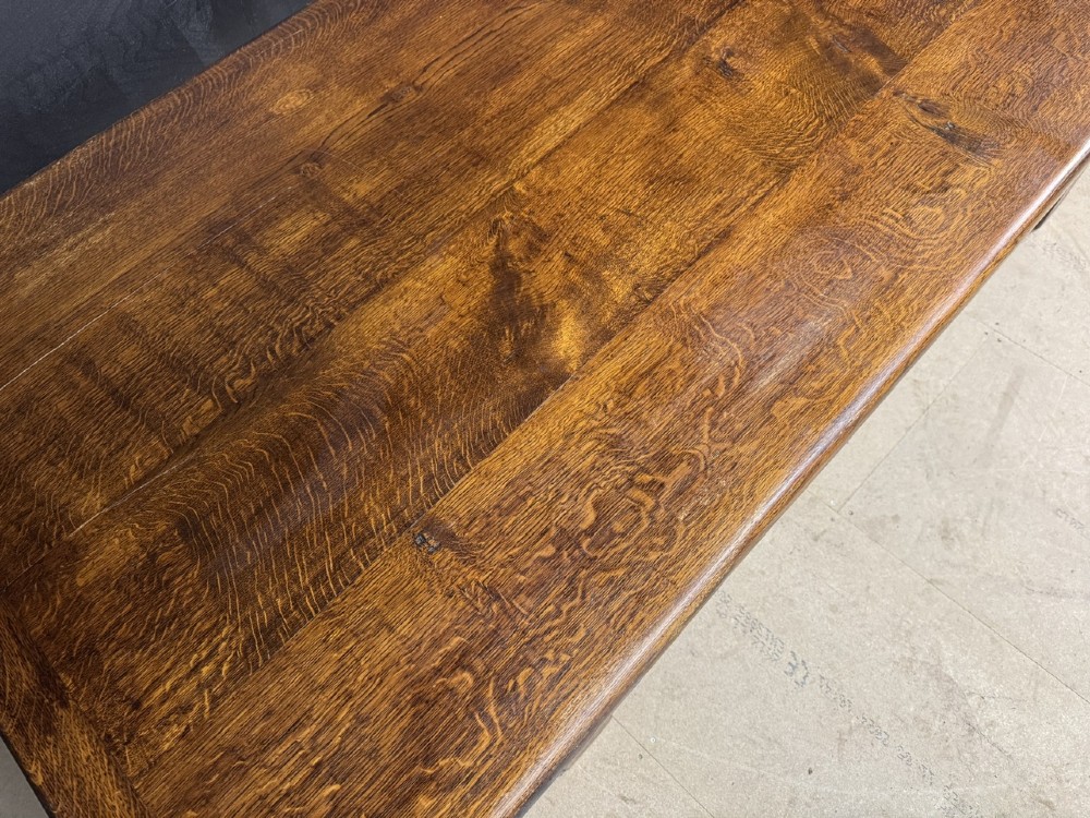 A long and deep solid dark oak farmhouse dining table featuring a plank top, moulded apron, and thick turned baluster legs joined by a floor-level stretcher. View XI