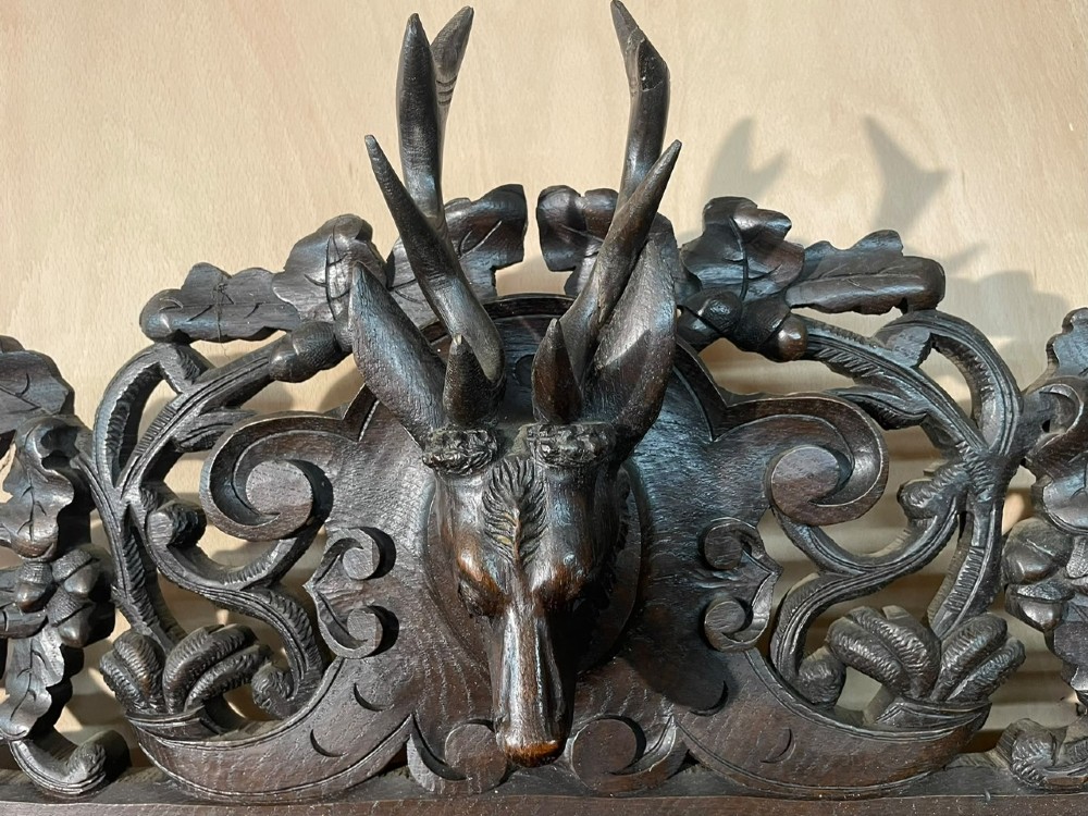 A dark oak French hunting sideboard featuring a carved stag head top pediment, open middle shelves, and lower cabinet doors decorated with carved game birds. View II