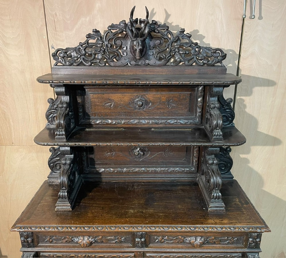 A dark oak French hunting sideboard featuring a carved stag head top pediment, open middle shelves, and lower cabinet doors decorated with carved game birds. View IV