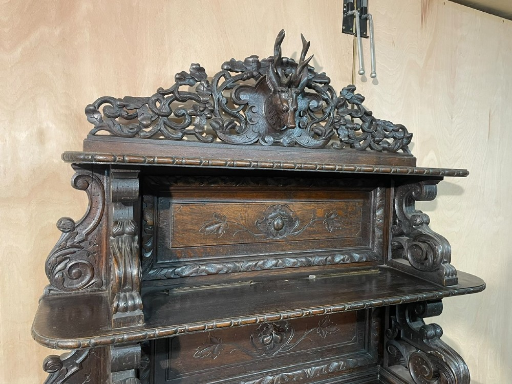 A dark oak French hunting sideboard featuring a carved stag head top pediment, open middle shelves, and lower cabinet doors decorated with carved game birds. View VII