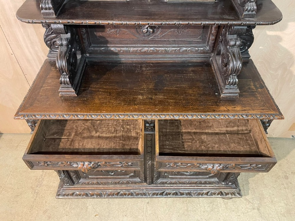 A dark oak French hunting sideboard featuring a carved stag head top pediment, open middle shelves, and lower cabinet doors decorated with carved game birds. View VIII