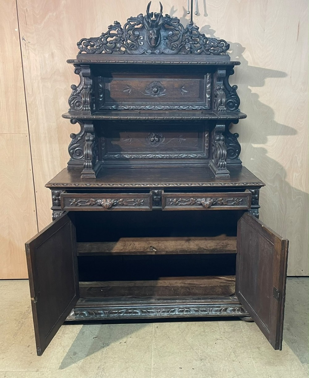 A dark oak French hunting sideboard featuring a carved stag head top pediment, open middle shelves, and lower cabinet doors decorated with carved game birds. View IX