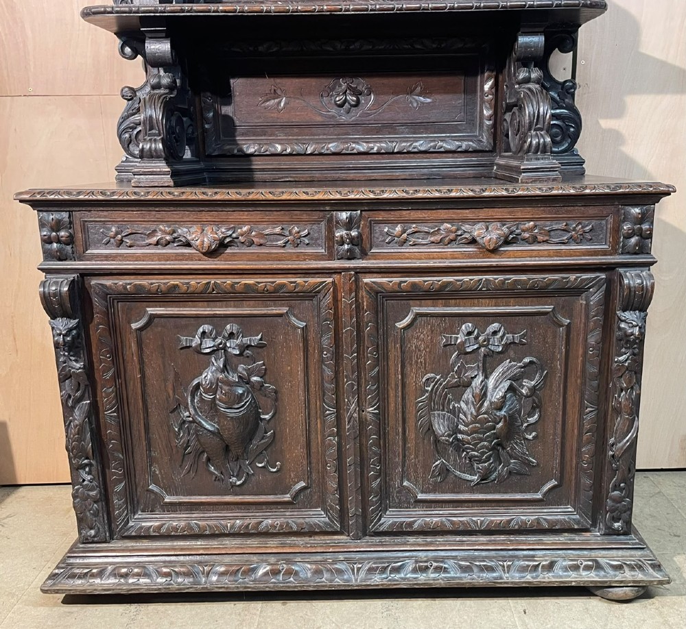 A dark oak French hunting sideboard featuring a carved stag head top pediment, open middle shelves, and lower cabinet doors decorated with carved game birds. View XI