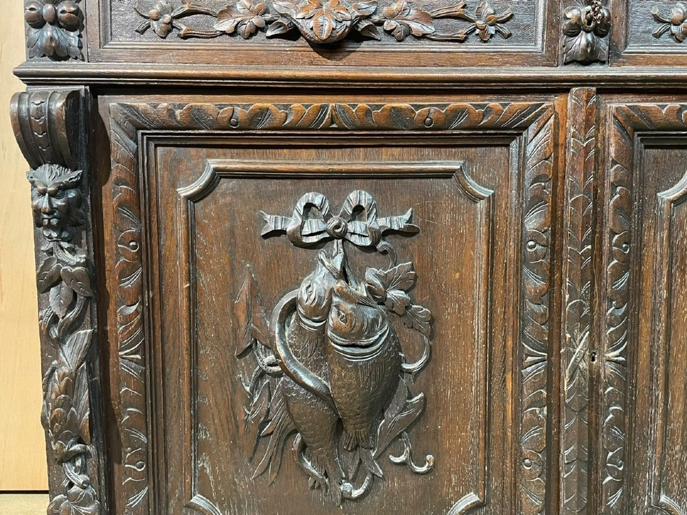 A dark oak French hunting sideboard featuring a carved stag head top pediment, open middle shelves, and lower cabinet doors decorated with carved game birds. View XII
