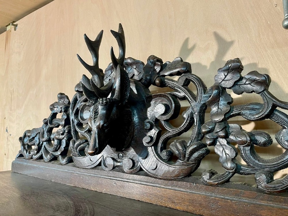 A dark oak French hunting sideboard featuring a carved stag head top pediment, open middle shelves, and lower cabinet doors decorated with carved game birds. View XIV