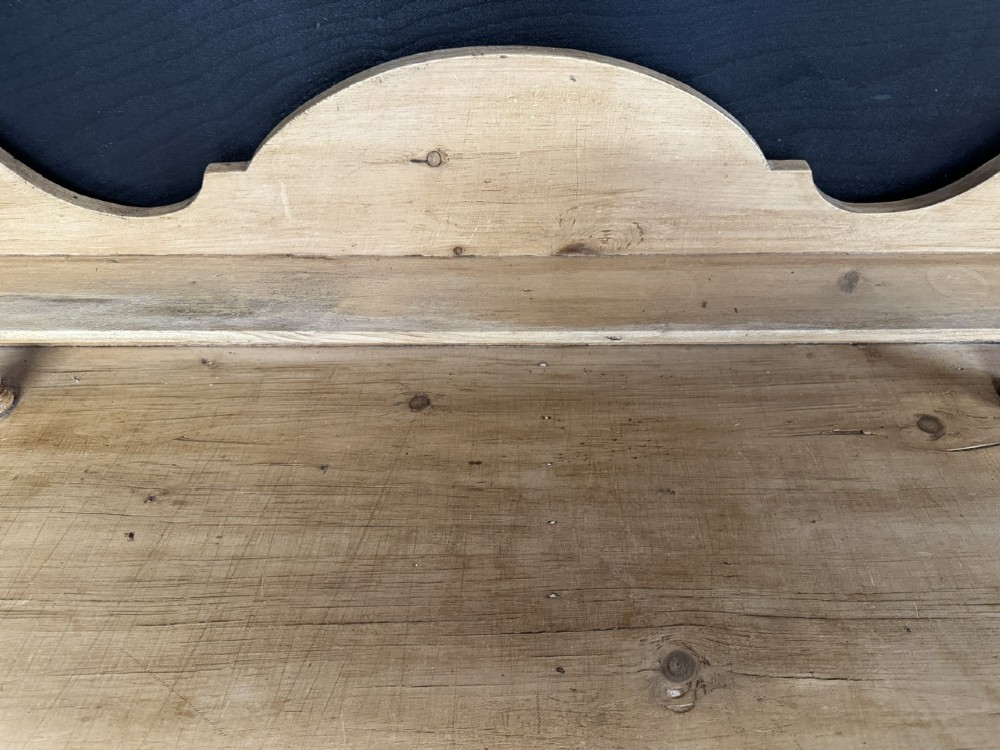 A small antique pine dresser base featuring three drawers on the left, a single panelled cupboard on the right, wooden knobs, turned bun feet, and a shaped back gallery shelf. View XII
