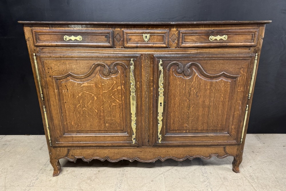 An 18th-century French provincial oak buffet featuring three top drawers above two carved panel doors with brass hardware. View III