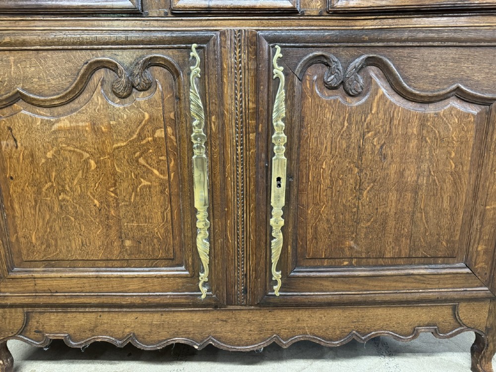 An 18th-century French provincial oak buffet featuring three top drawers above two carved panel doors with brass hardware. View V