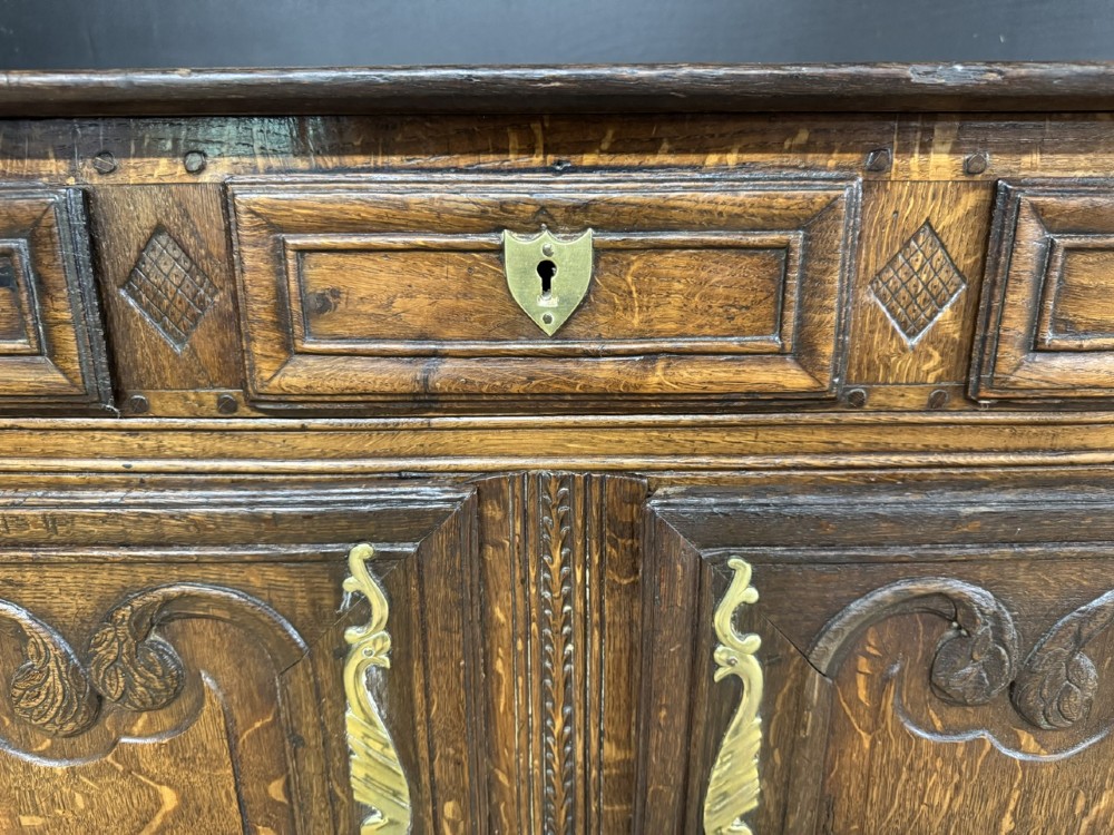 An 18th-century French provincial oak buffet featuring three top drawers above two carved panel doors with brass hardware. View VIII