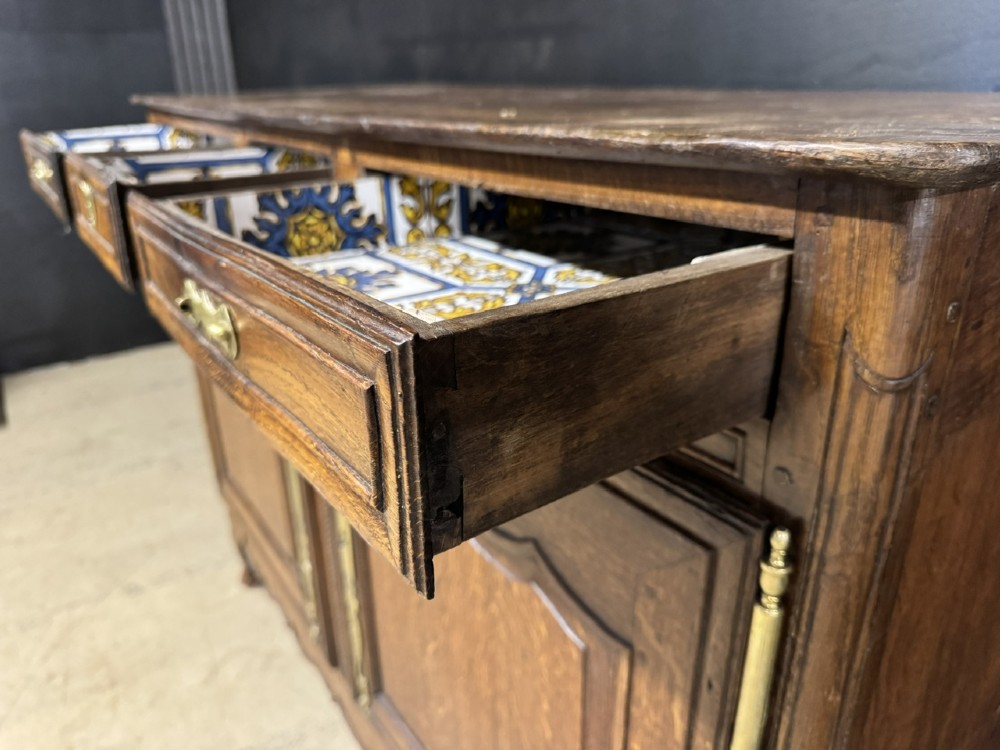 An 18th-century French provincial oak buffet featuring three top drawers above two carved panel doors with brass hardware. View XII