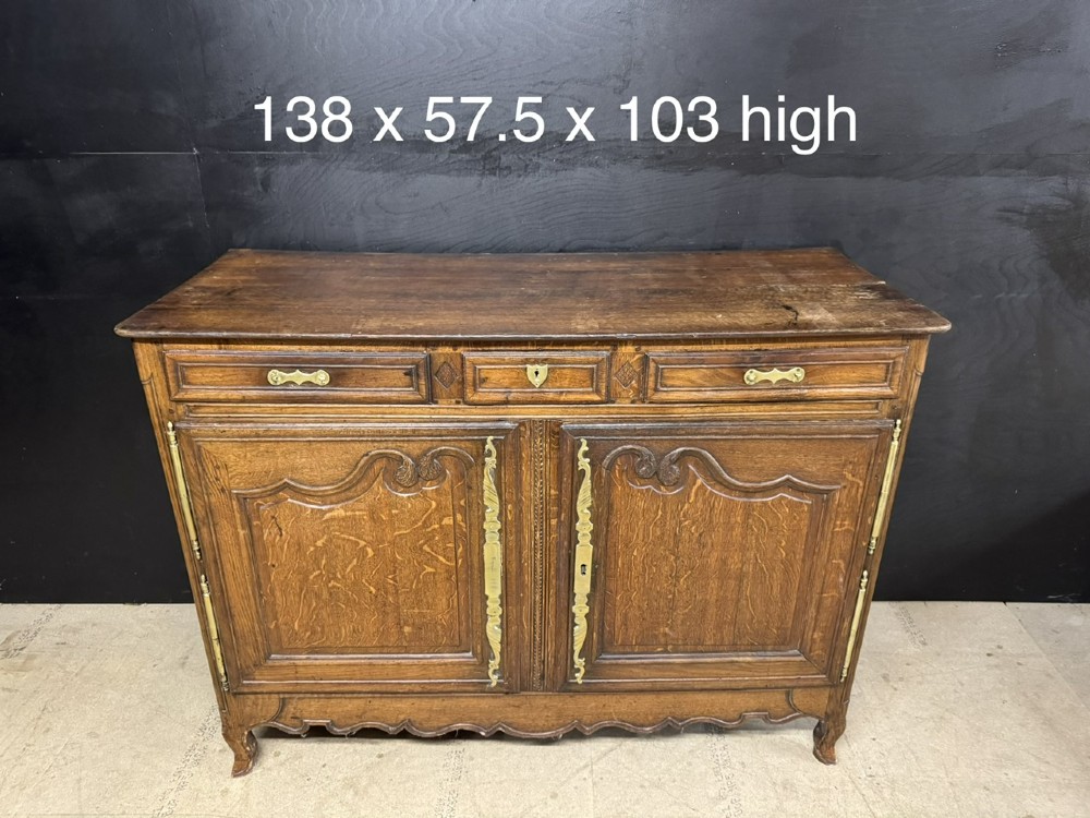 An 18th-century French provincial oak buffet featuring three top drawers above two carved panel doors with brass hardware. View XIII