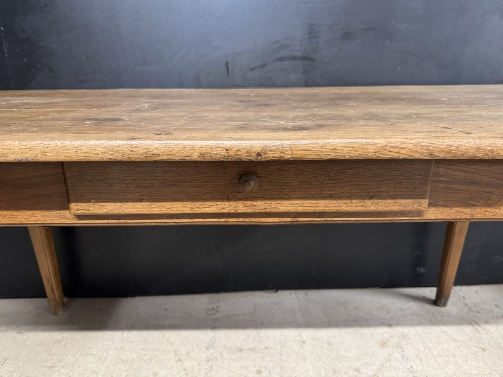 A rectangular natural oak French Normandy country table featuring a simple plank top, tapered legs, and a single frieze drawer. View V