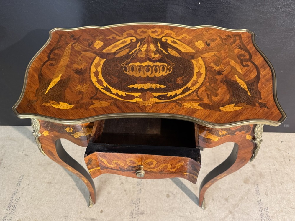 A French Louis XV style marquetry side table featuring cabriole legs, decorative brass mounts, and detailed floral wood inlay across the serpentine top and drawer. View IV