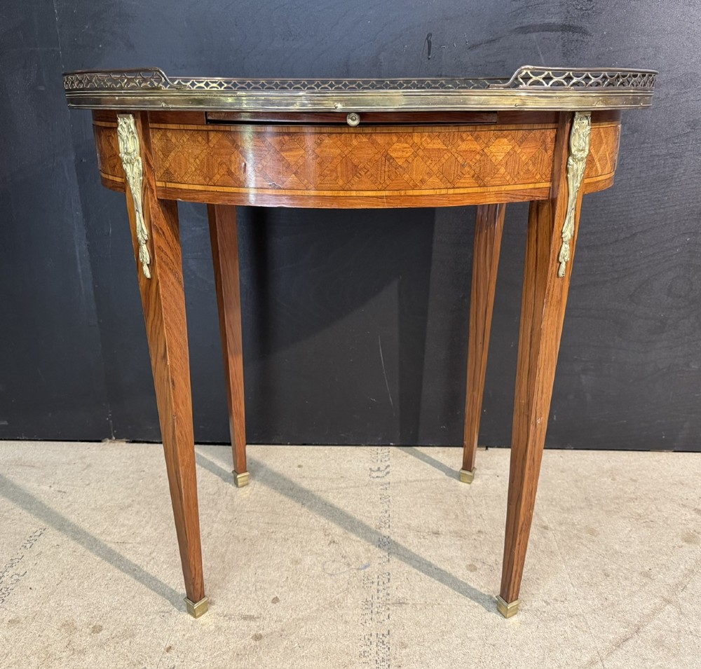 An oval French side table featuring a red veined marble top with a pierced brass gallery, geometric parquetry apron, and four tapered legs adorned with brass mounts. View III