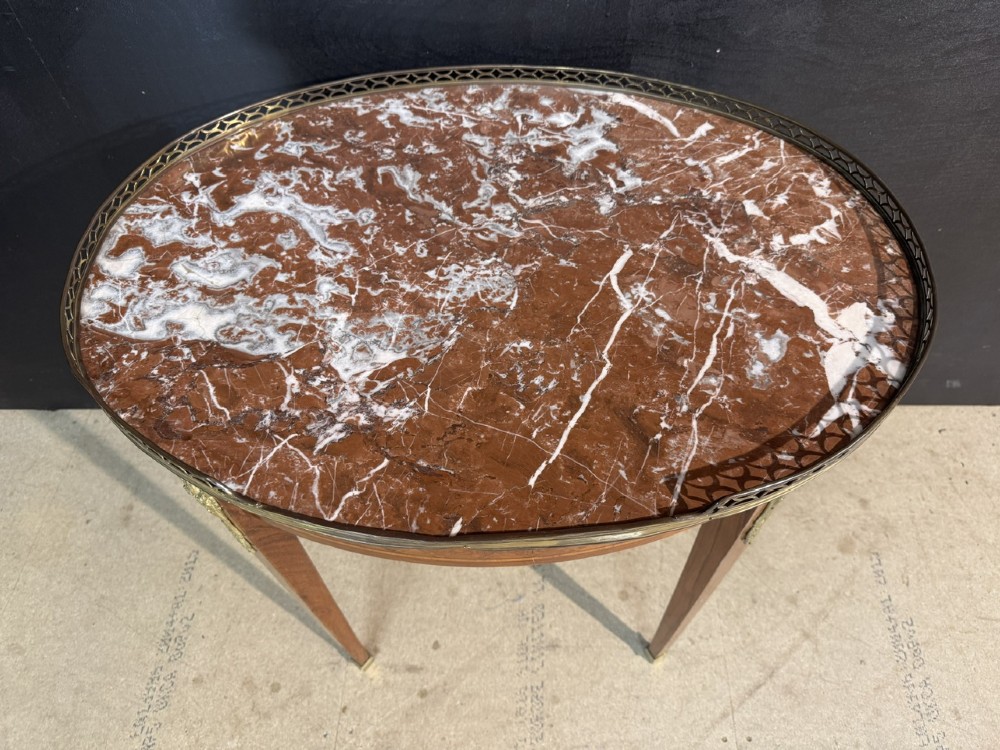 An oval French side table featuring a red veined marble top with a pierced brass gallery, geometric parquetry apron, and four tapered legs adorned with brass mounts. View IV
