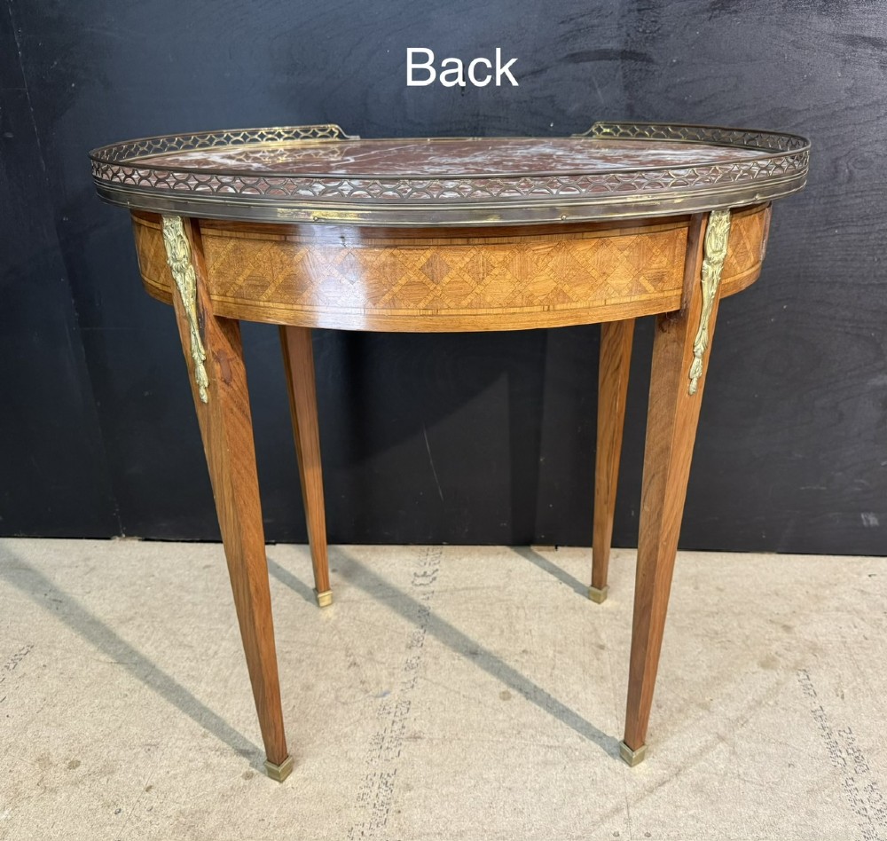 An oval French side table featuring a red veined marble top with a pierced brass gallery, geometric parquetry apron, and four tapered legs adorned with brass mounts. View XI