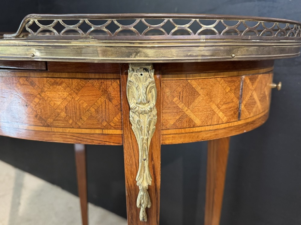 An oval French side table featuring a red veined marble top with a pierced brass gallery, geometric parquetry apron, and four tapered legs adorned with brass mounts. View XII