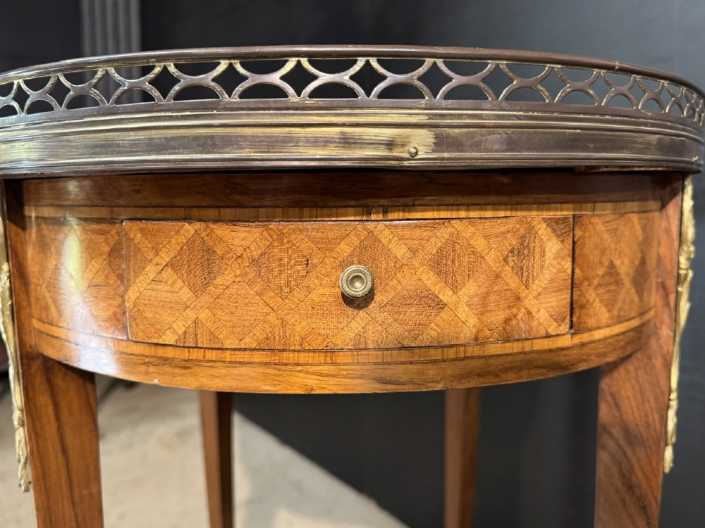 An oval French side table featuring a red veined marble top with a pierced brass gallery, geometric parquetry apron, and four tapered legs adorned with brass mounts. View XIII