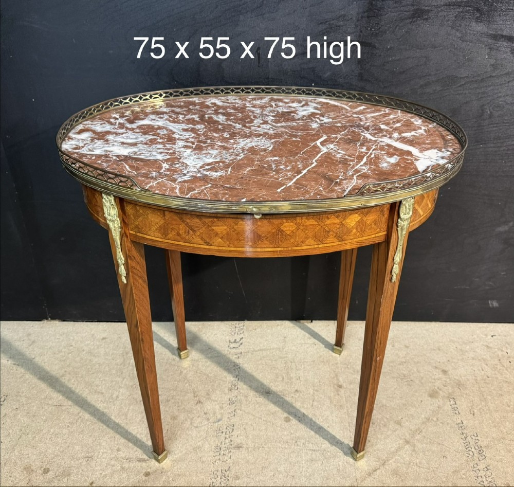 An oval French side table featuring a red veined marble top with a pierced brass gallery, geometric parquetry apron, and four tapered legs adorned with brass mounts. View XV