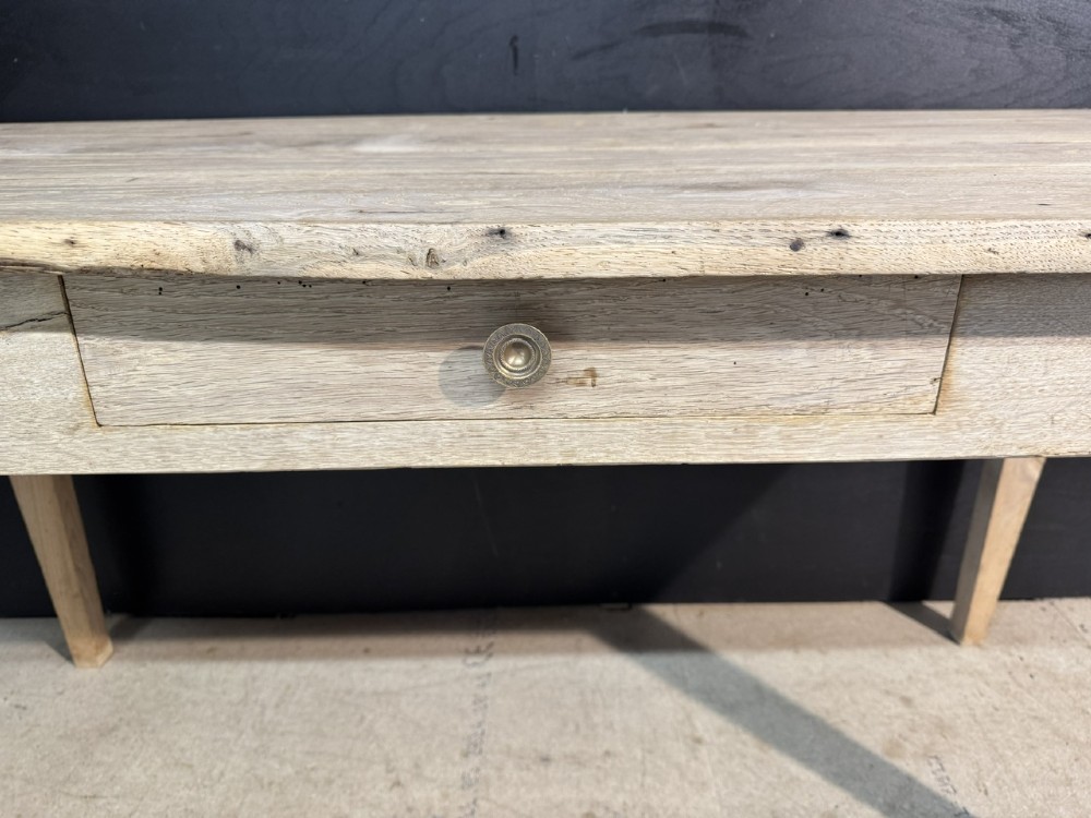 A rustic light oak French Normandy table featuring a flat plank top, a single central frieze drawer with a metal knob, and four square tapered legs. View III