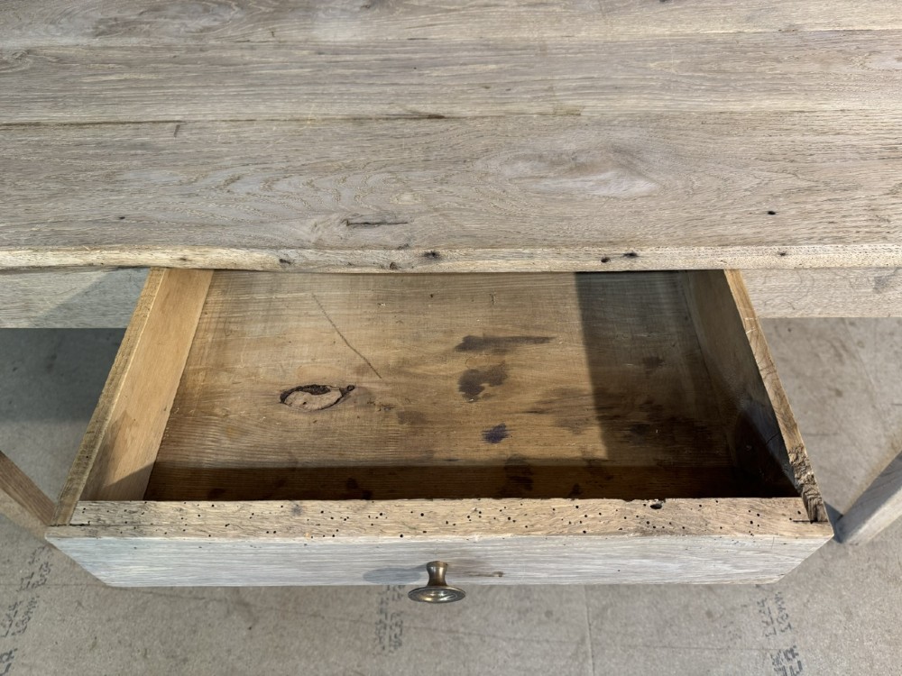 A rustic light oak French Normandy table featuring a flat plank top, a single central frieze drawer with a metal knob, and four square tapered legs. View IV