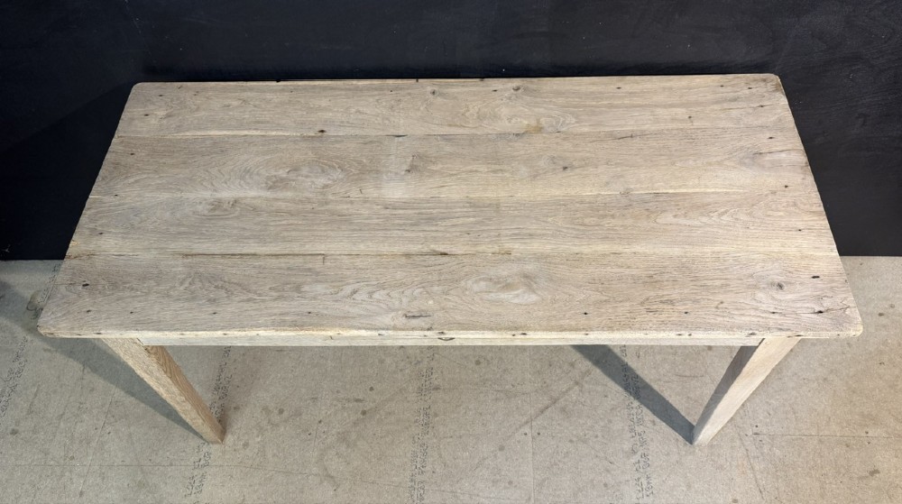 A rustic light oak French Normandy table featuring a flat plank top, a single central frieze drawer with a metal knob, and four square tapered legs. View V
