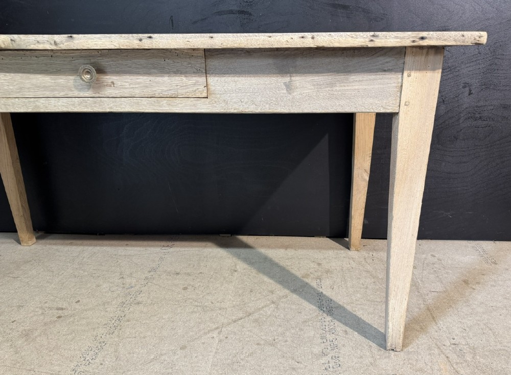 A rustic light oak French Normandy table featuring a flat plank top, a single central frieze drawer with a metal knob, and four square tapered legs. View VI