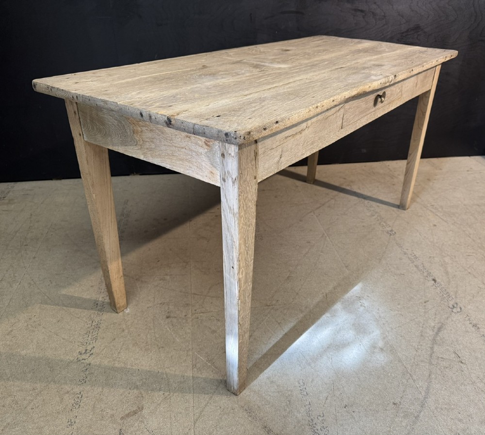 A rustic light oak French Normandy table featuring a flat plank top, a single central frieze drawer with a metal knob, and four square tapered legs. View VII
