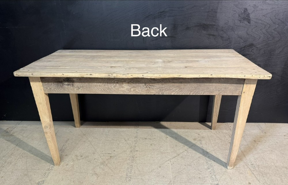 A rustic light oak French Normandy table featuring a flat plank top, a single central frieze drawer with a metal knob, and four square tapered legs. View X