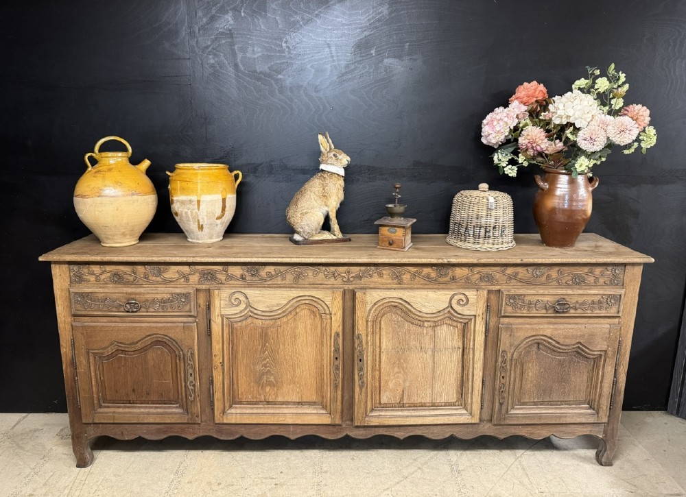 A long French oak enfilade featuring four cupboards with arched fielded panels, decorative floral carvings along the frieze, and two side drawers. View II