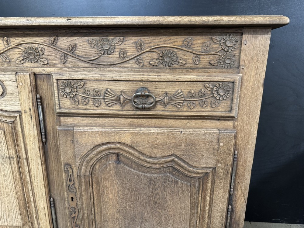 A long French oak enfilade featuring four cupboards with arched fielded panels, decorative floral carvings along the frieze, and two side drawers. View IV