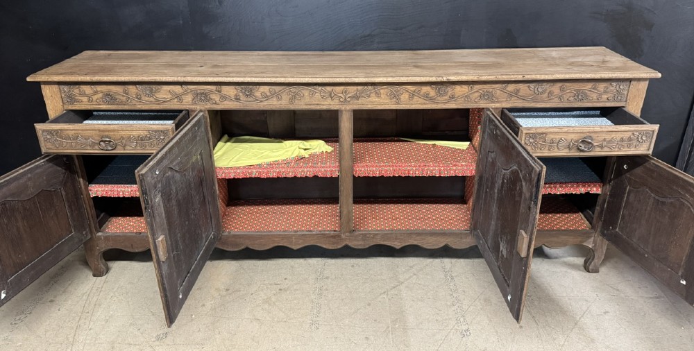 A long French oak enfilade featuring four cupboards with arched fielded panels, decorative floral carvings along the frieze, and two side drawers. View V