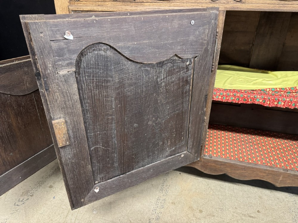 A long French oak enfilade featuring four cupboards with arched fielded panels, decorative floral carvings along the frieze, and two side drawers. View VII