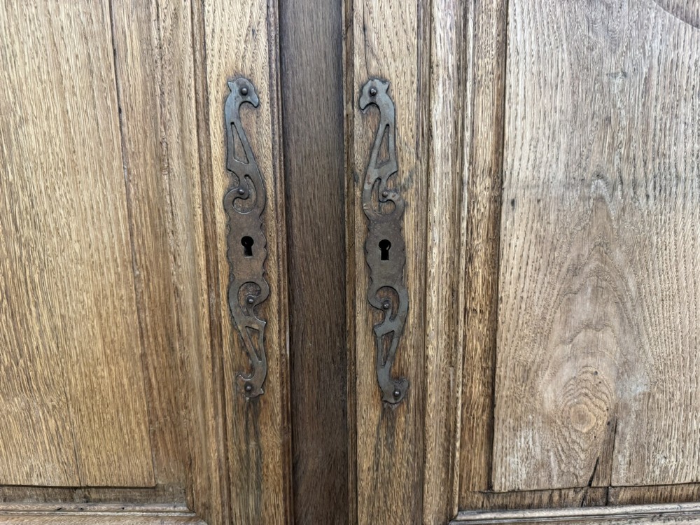 A long French oak enfilade featuring four cupboards with arched fielded panels, decorative floral carvings along the frieze, and two side drawers. View VIII
