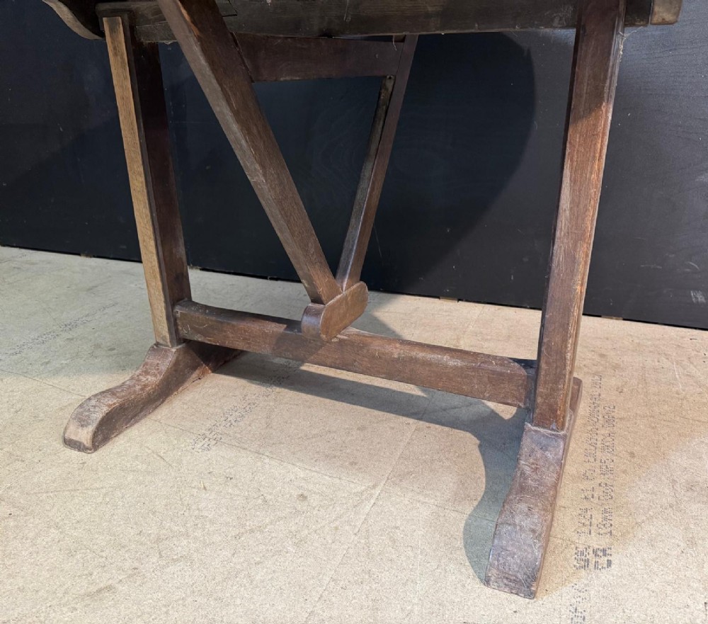 A circular rustic French wine tasting table made of pale planked timber tilted vertically on a wooden trestle base. View VIII