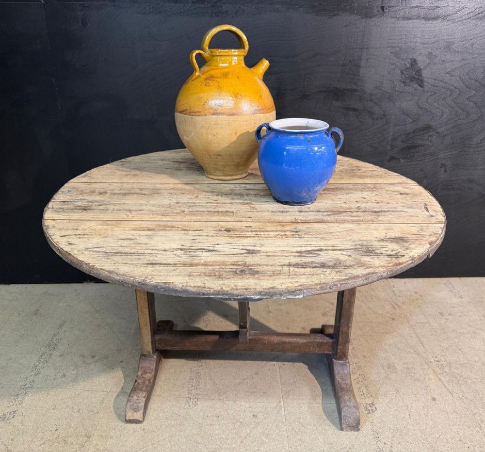 A circular rustic French wine tasting table made of pale planked timber tilted vertically on a wooden trestle base. View IX