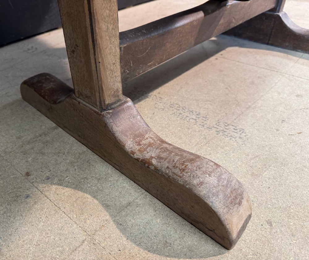 A circular rustic French wine tasting table made of pale planked timber tilted vertically on a wooden trestle base. View X