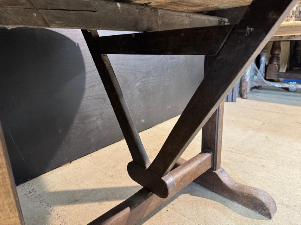 A circular rustic French wine tasting table made of pale planked timber tilted vertically on a wooden trestle base. View XI