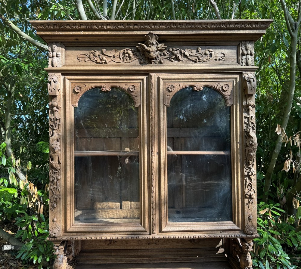 A two-piece bleached oak hunting cabinet featuring hand-carved relief panels of game birds, glazed upper doors, and a decorative mask pediment. View IV