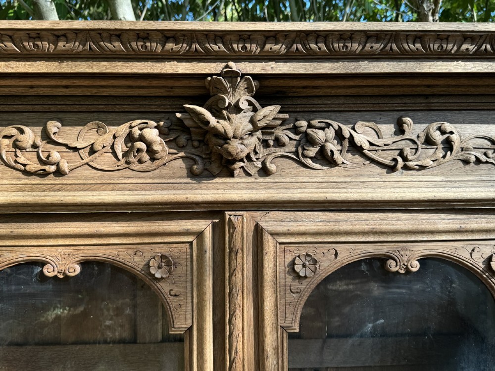 A two-piece bleached oak hunting cabinet featuring hand-carved relief panels of game birds, glazed upper doors, and a decorative mask pediment. View VII
