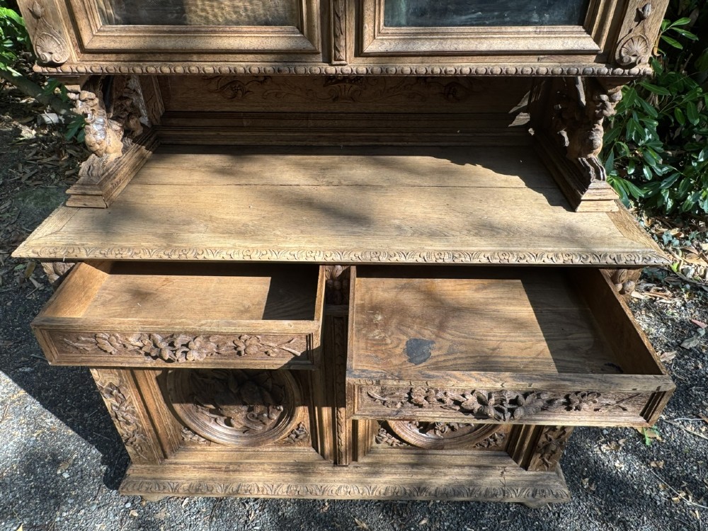 A two-piece bleached oak hunting cabinet featuring hand-carved relief panels of game birds, glazed upper doors, and a decorative mask pediment. View IX