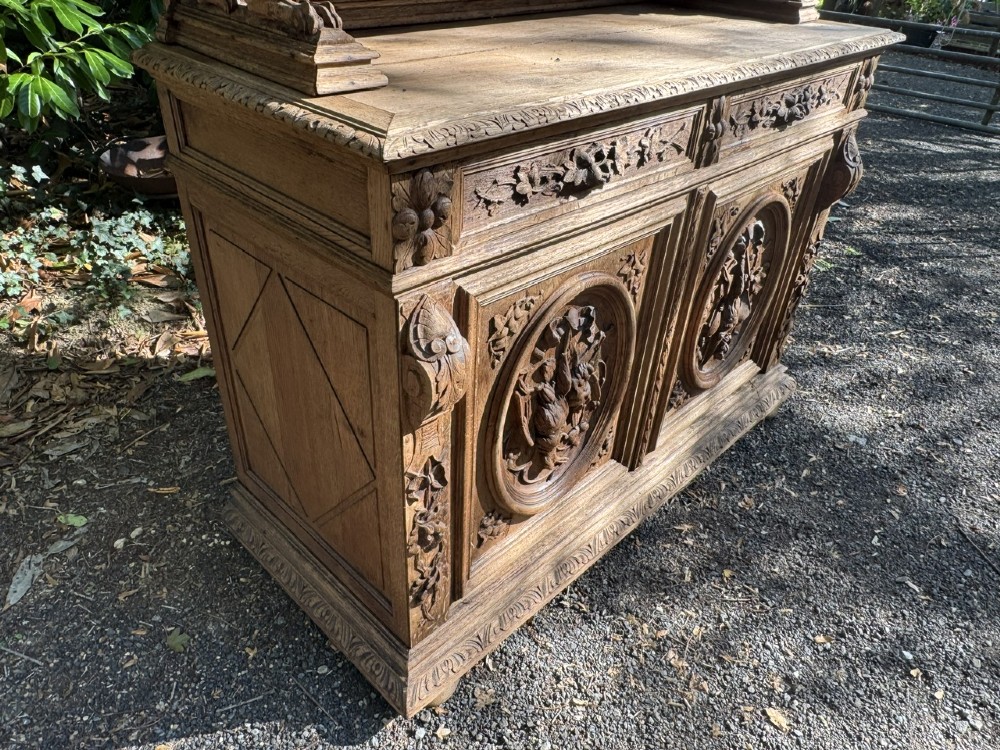 A two-piece bleached oak hunting cabinet featuring hand-carved relief panels of game birds, glazed upper doors, and a decorative mask pediment. View XIII