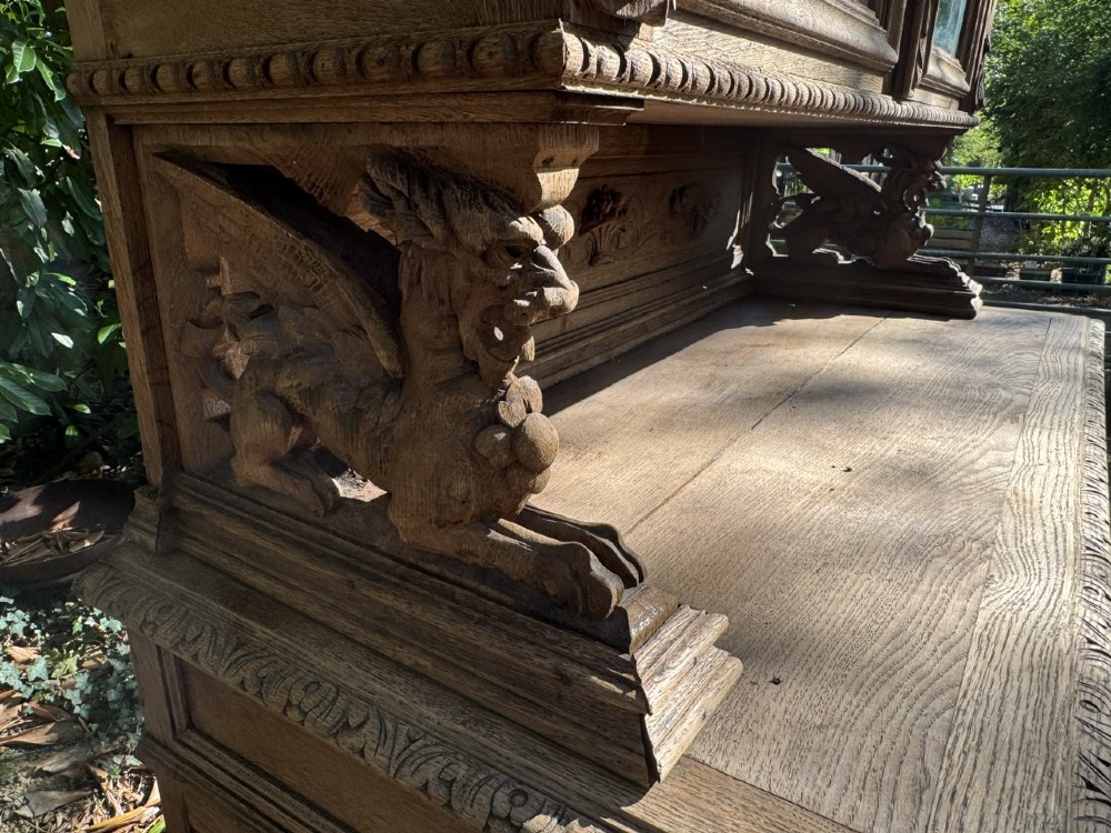 A two-piece bleached oak hunting cabinet featuring hand-carved relief panels of game birds, glazed upper doors, and a decorative mask pediment. View XV