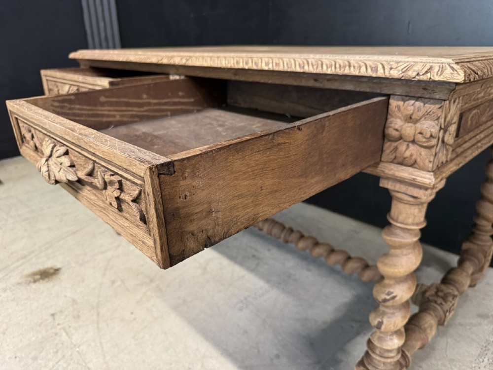 A French bleached oak writing desk featuring hand-carved floral drawer fronts, egg-and-dart moulding, turned barley twist legs, and an H-stretcher base. View V