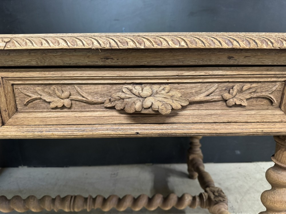 A French bleached oak writing desk featuring hand-carved floral drawer fronts, egg-and-dart moulding, turned barley twist legs, and an H-stretcher base. View VI